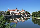 Stadtansicht mit Schloss und Brücke, Spiegelung im Fluss, blauer Himmel, Bäume am Ufer