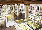Archäologisches Museum der Stadt Kelheim Museumsausstellung mit Vitrinen, archäologischen Funden und einer Person vor Säulen in historischem Gebäude